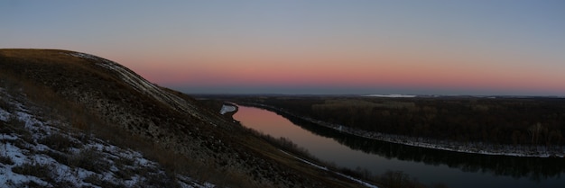 Vue panoramique sur la rivière depuis la falaise. Ciel du soir après le coucher du soleil.