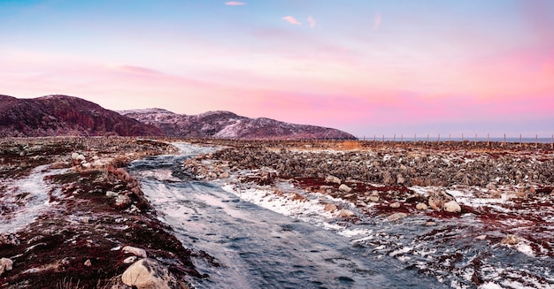 Vue panoramique de la route arctique glissante glacée à travers la toundra. Route d'hiver du nord. Coucher de soleil polaire magenta. Teriberka d'hiver.