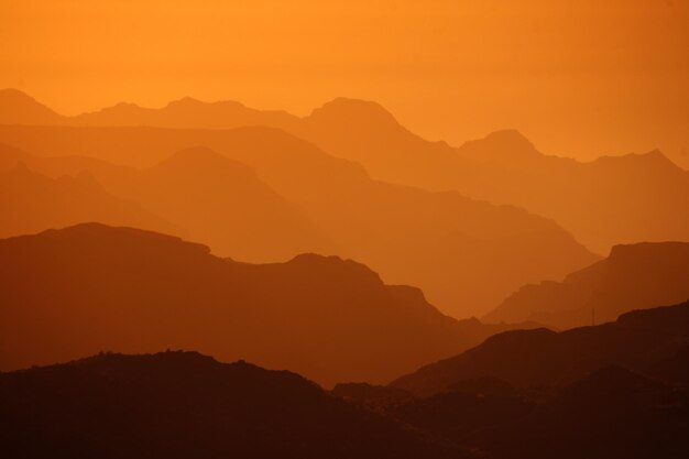 Vue panoramique des silhouettes de montagnes sur un ciel orange
