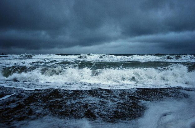 Vue panoramique des vagues dans la mer contre un ciel nuageux