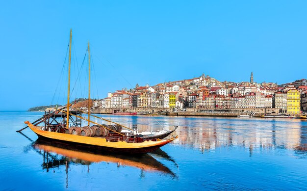 Photo vue panoramique de la vieille ville de porto le bateau rabelo au premier plan sur le fleuve douro porto portugal