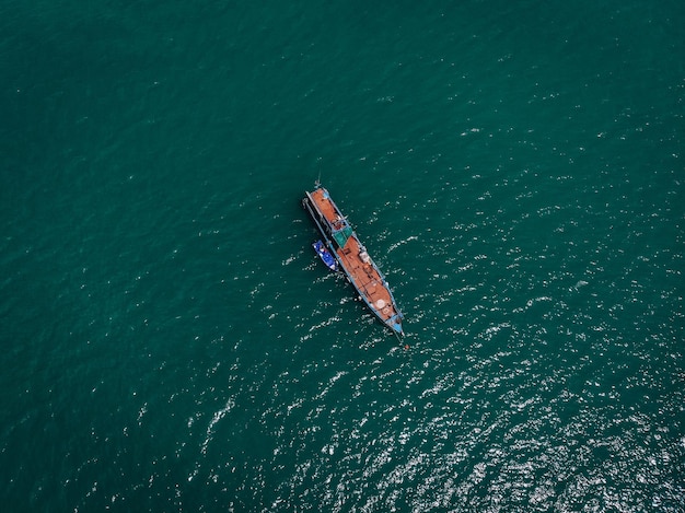 Vue par drone du grand vieux bateau à moteur bleu avec un immense pont vide dans la mer bleue, canot de sauvetage violet à ses côtés ; notion de navires.