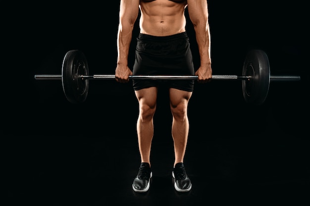 Vue partielle du bodybuilder musculaire exerçant avec des haltères lourds isolé sur fond noir
