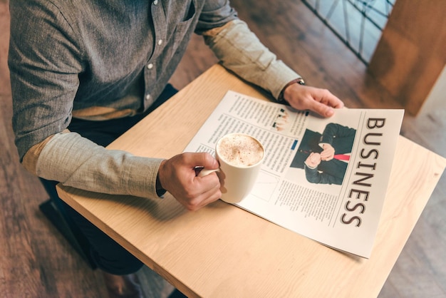 Vue Partielle De L'homme D'affaires Avec Une Tasse De Café Et Un Journal D'affaires Au Café