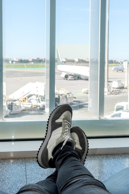 Vue partielle des jambes d'un homme allongé dans un fauteuil en attente à l'aéroport pour son vol de départ
