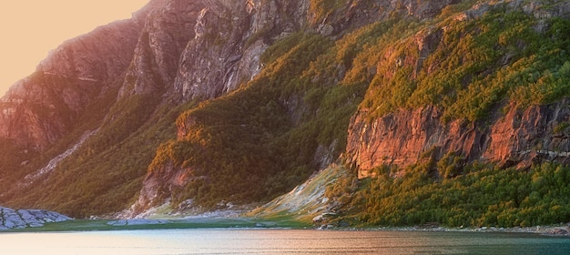 Vue sur le paysage de l'eau du lac et des montagnes au coucher du soleil en Norvège Océan ou mer calme et serein à l'aube dans une campagne paisible isolée Paysage de fjord naturel relaxant avec des falaises abruptes à l'aube