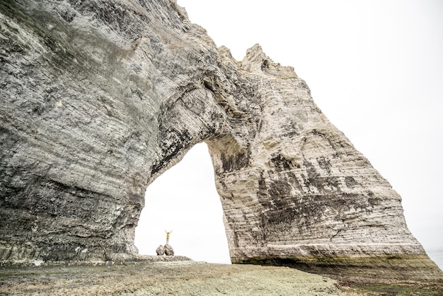 Vue paysage sur l'immense falaise de pierre avec un trou et un voyageur debout à l'intérieur