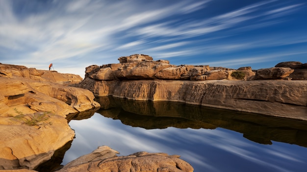 Vue paysage d'un lac dans un Grand Canyon en Thaïlande avec petit photographe loin sur un rocher