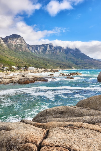 Vue paysage de l'océan plage mer nuages ciel bleu avec espace de copie sur Camps Bay Cape Town Afrique du Sud Vagues de marée se lavant sur les rochers ou les rochers du rivage Arrière-plan des montagnes des Douze Apôtres