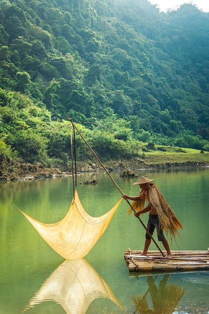 Photo vue de pêcheurs pêchant sur la rivière dans la montagne thung dans la province de tra linh cao bang au vietnam avec la nature nuageuse du lac concept de voyage et de paysage