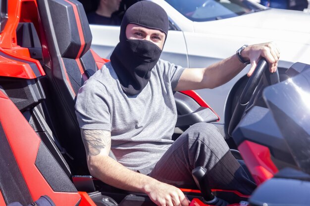 Photo vue d'une personne conduisant un homme de voiture avec un masque noir dans la voiture