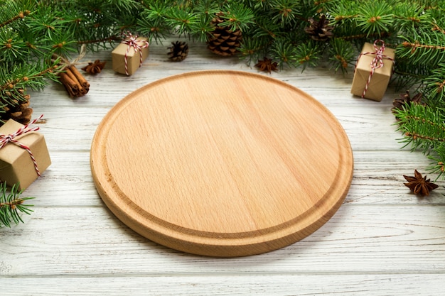 Vue de perspective. Assiette ronde en bois vide sur planche de Noël en bois. concept de dîner de vacances avec décor de nouvel an