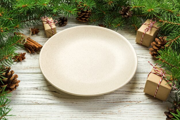 Vue de perspective. Assiette vide rond en céramique sur fond de Noël en bois. plat de dîner de fête avec décor de nouvel an