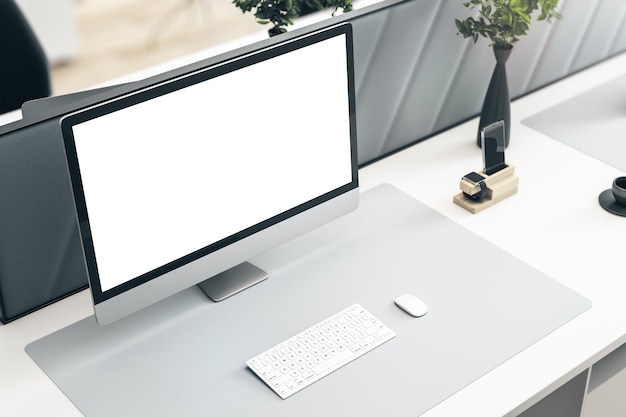 Vue en perspective sur un écran de moniteur moderne blanc vierge avec un espace pour votre logo ou votre texte sur une surface lumineuse élégante avec une maquette de rendu 3D de plante verte et de clavier blanc