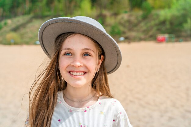 Vue d'une petite fille dans un chapeau à larges bords debout au bord de la mer sur la plage