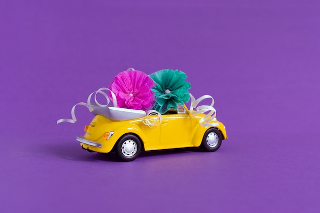 Vue d'une petite voiture jaune colorée dans laquelle les fleurs reposent sur un violet.