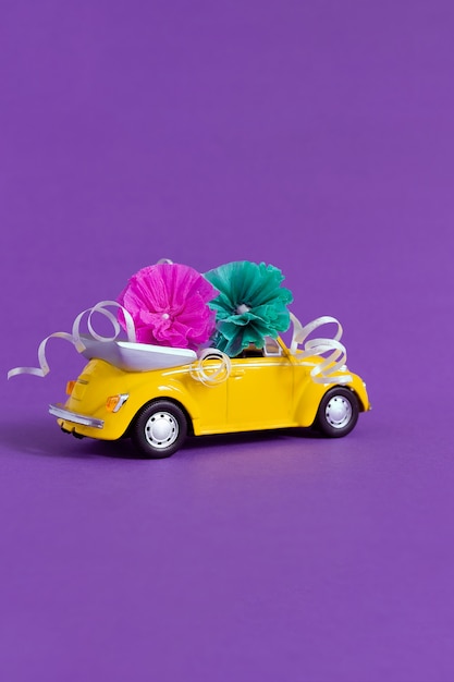 Vue d'une petite voiture orange vif dans laquelle les fleurs reposent sur un violet.