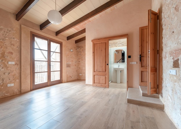 Vue d'une pièce vide avec parquet poutres apparentes balcon dans une maison rénovée