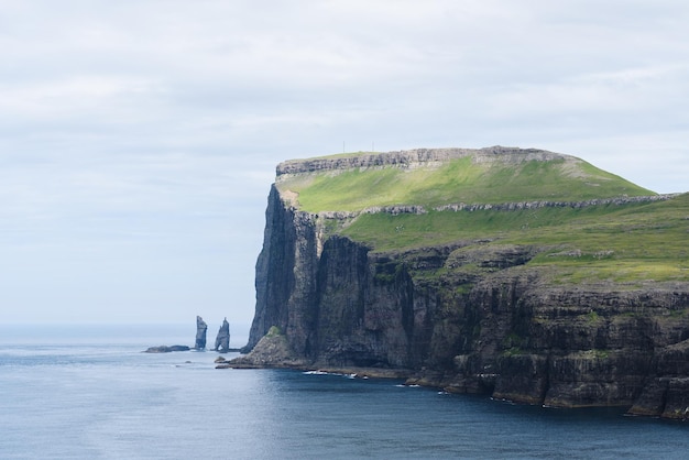 Photo vue des piles de mer de risin og kellingin depuis le village de tjornuvik, dans les îles féroé