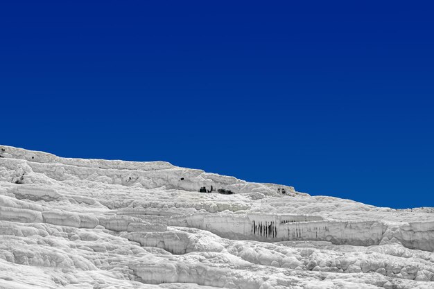 Vue sur les piscines et terrasses en travertin naturel à pamukkale un jour d'été texture d'un mur blanc