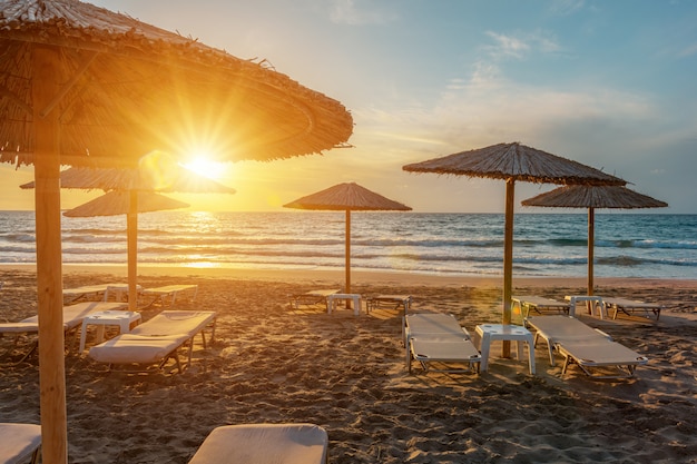 Vue de la plage tropicale avec parasols pendant le coucher du soleil