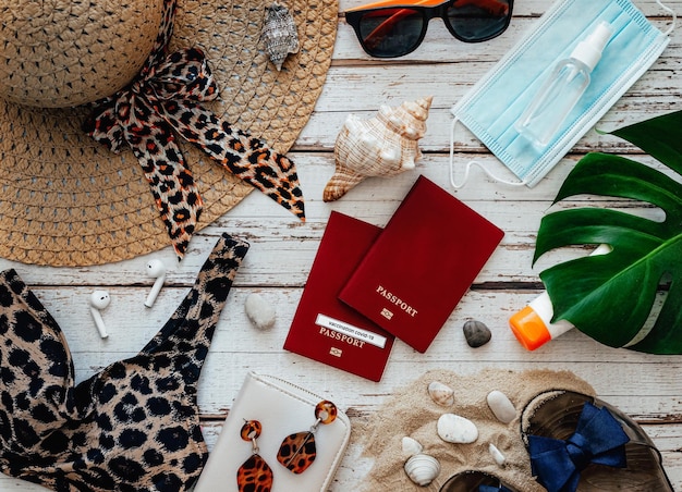 Vue plate des accessoires de vacances à la plage maillot de bain lunettes passeport et autres sur fond de bois concept de vacances en cas de pandémie de coronovirus