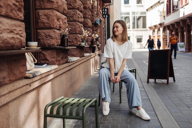 Vue pleine longueur d'une jolie femme assise au café en jean bleu