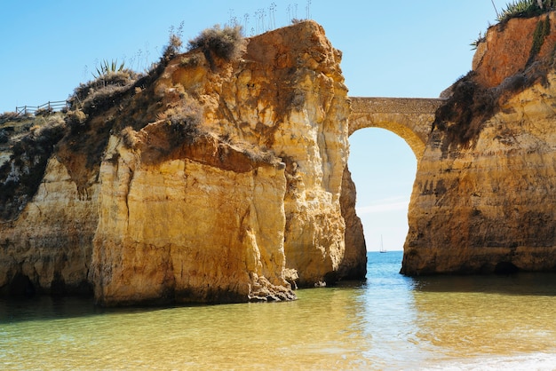 Photo vue sur pont voûté avec voilier à lagos, algarve, portugal