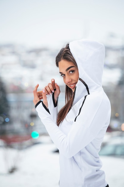 Vue de portrait de jeune fille active sportive motivée et concentrée souriante satisfaite réchauffement en sportswear d'hiver la nature enneigée le matin.