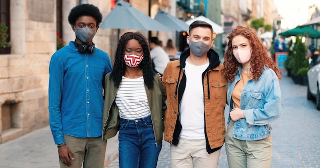 Vue portrait à la taille de la joyeuse compagnie des meilleurs amis portant des masques de protec...