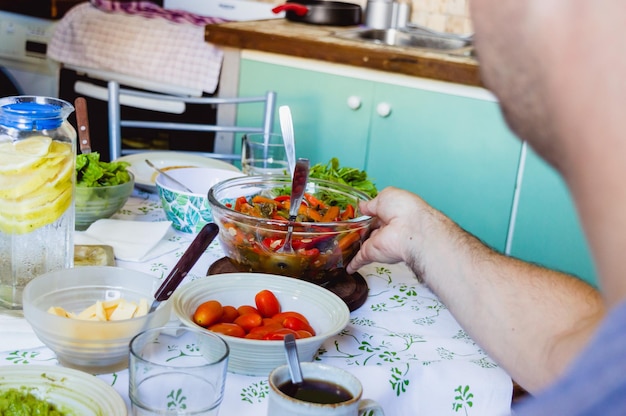 Vue à la première personne d'un homme caucasien prenant un bol avec des légumes cuits de la table