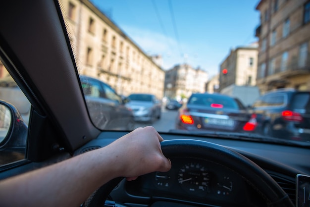 Vue à la première personne homme conduisant une voiture dans les rues de la ville trafic urbain