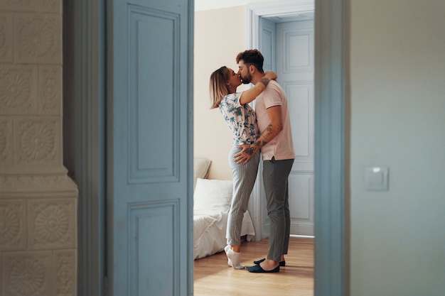 Vue de profil d'aimer jeune couple étreindre en se tenant debout dans leur chambre