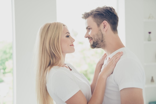 Vue de profil de côté de beau couple en t-shirts blancs embrassant en se regardant