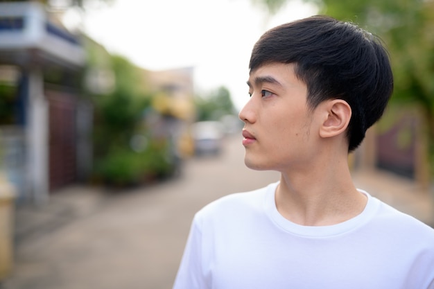 Vue de profil du jeune homme asiatique pensant dans la rue