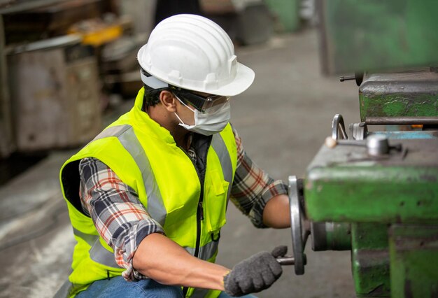 Vue de profil du jeune technicien en chemise à carreaux inspectant la machine industrielle