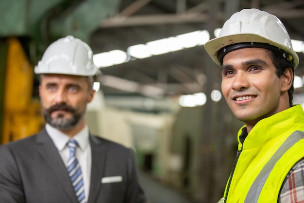 Vue de profil du jeune technicien en chemise à carreaux inspectant la machine industrielle