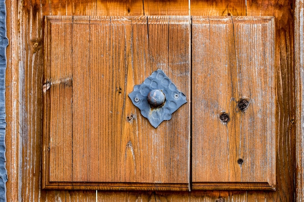 Vue rapprochée d'une ancienne porte rustique, massive, en bois, avec des sculptures décoratives.