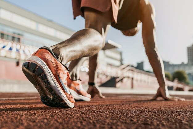 Photo vue rapprochée d'un athlète qui se prépare à courir sur la piste.