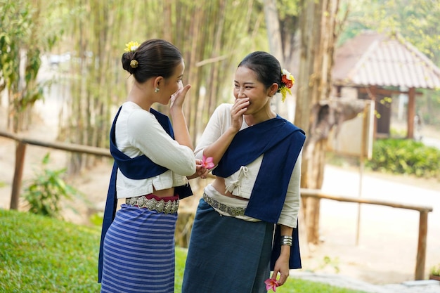 Vue rapprochée d'une belle jeune femme thaïlandaise en tenue traditionnelle du nord de la Thaïlande en train de bavarder et de se taquiner sur un fond flou