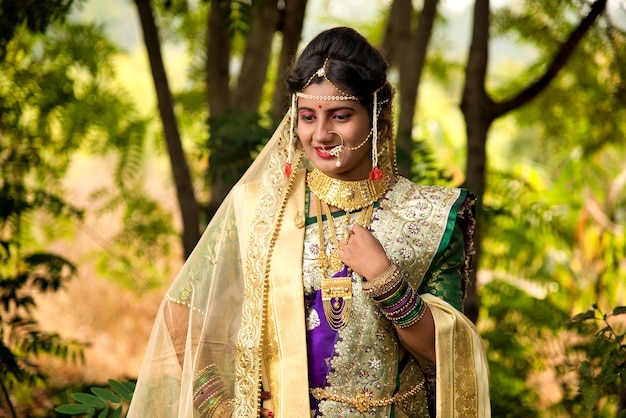Vue rapprochée de la belle mariée indienne en saree traditionnelle posant en plein air dans un parc