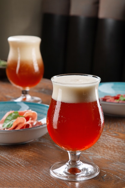 Vue rapprochée sur la bière ambrée froide dans un verre avec collation au bar sur table