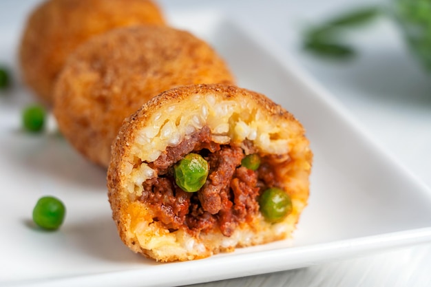 Vue rapprochée de boules de riz italiennes Arancini maison frites et farcies de hachis et de pois