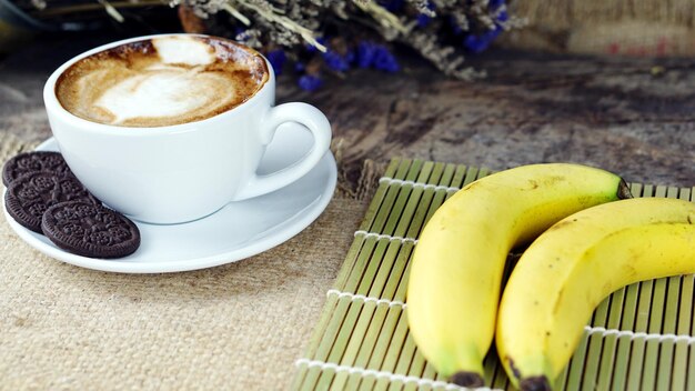 Photo vue rapprochée d'un cappuccino avec des bananes sur la table