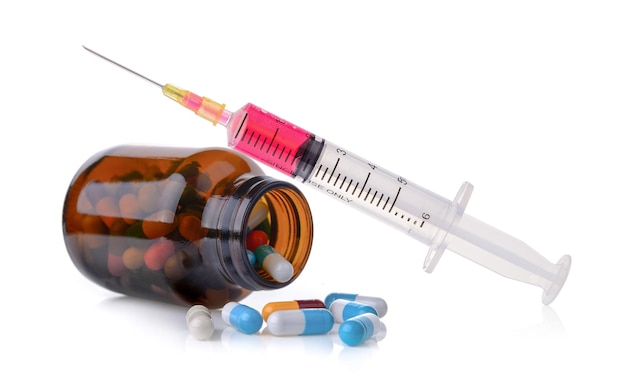 Vue rapprochée des capsules qui sortent du flacon par seringue sur un fond blanc