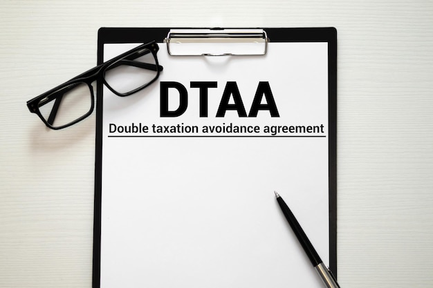 Vue rapprochée de la carte d'homme d'affaires avec le texte de l'acronyme DTAA DOUBLE TAXATION AVOIDANCE AGREEMENT