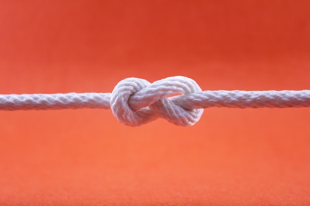 Photo vue rapprochée d'une corde attachée sur du métal sur un fond rouge