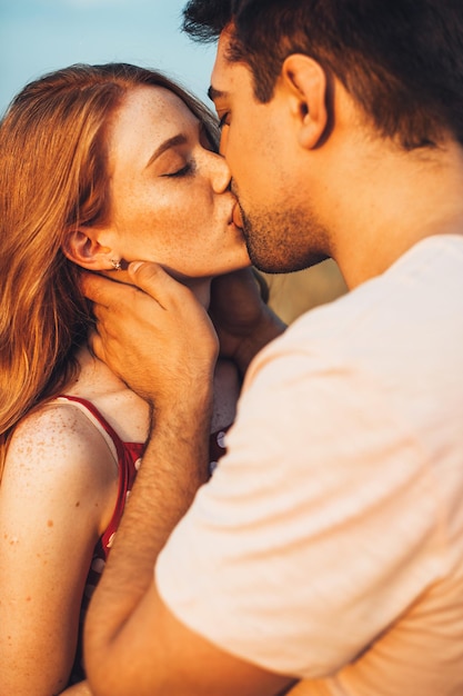 Vue rapprochée d'un couple s'embrassant dans un champ ensoleillé de blé beau paysage d'été campagne lan...