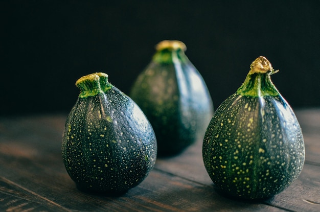 Photo vue rapprochée de courgettes rondes sur table sur un fond noir