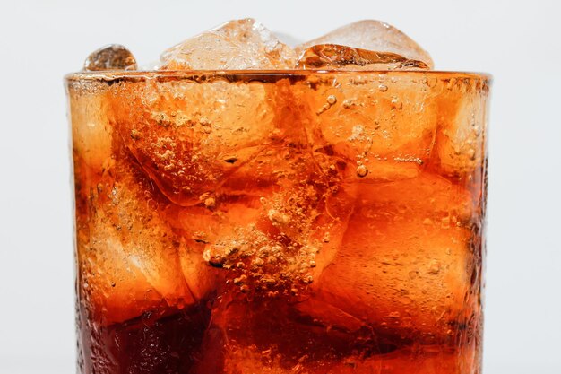 Photo vue rapprochée de cubes de glace dans le cola sur un fond blanc